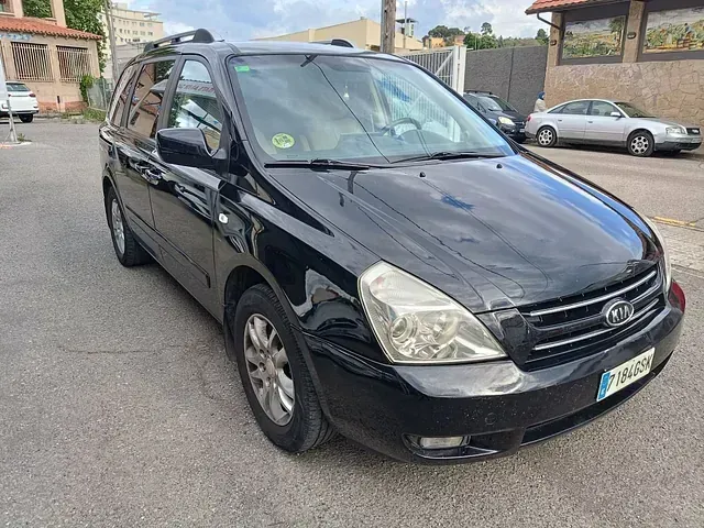 Un coche negro está estacionado al costado de la carretera frente a un edificio.