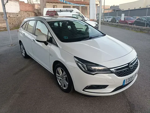 Un Opel Astra blanco está estacionado en un estacionamiento.