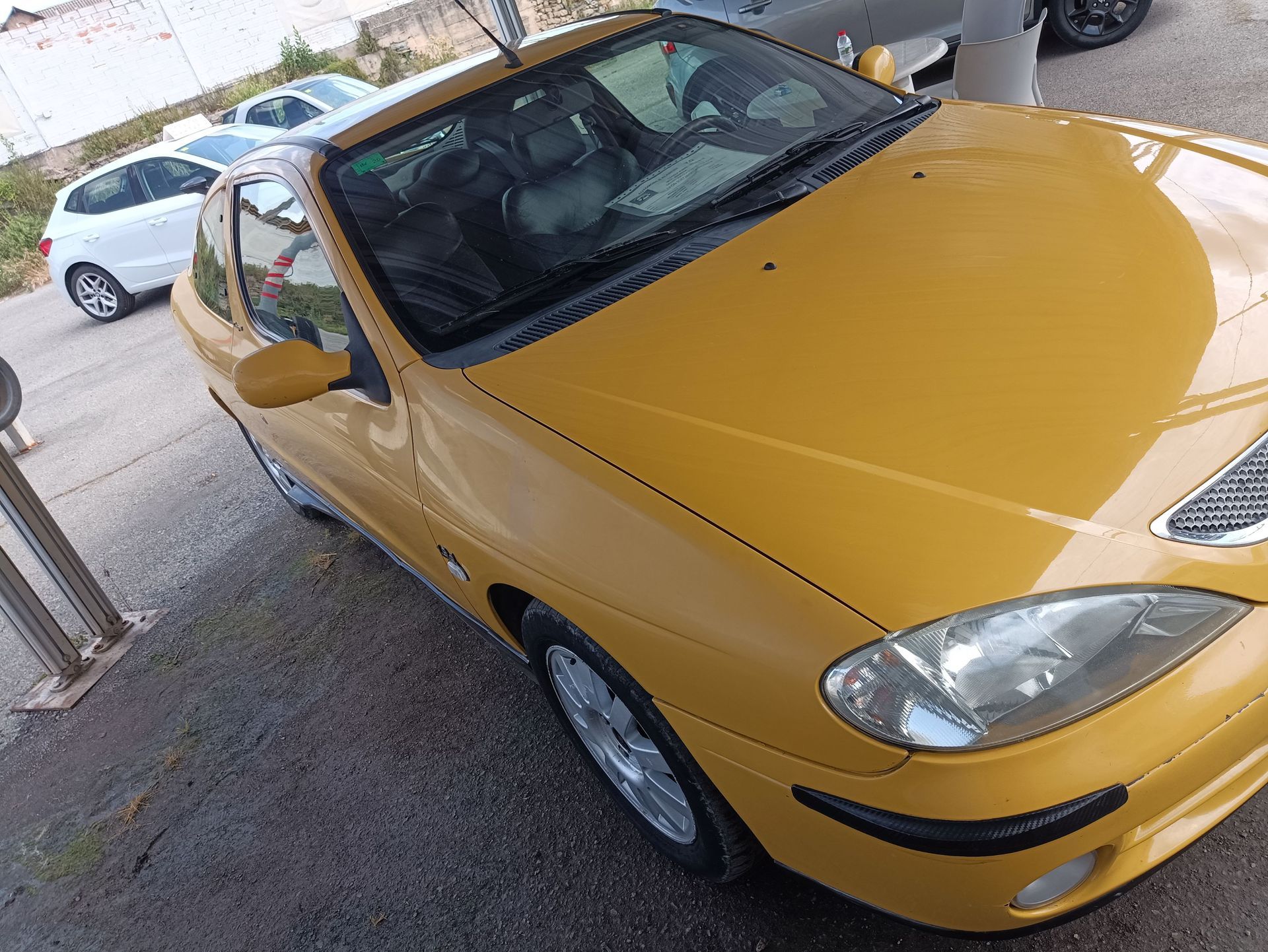Coche compacto plateado aparcado en un estacionamiento, visto desde el lado delantero izquierdo.