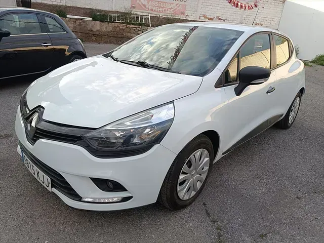 Un coche blanco está aparcado en un estacionamiento al lado de un coche negro.