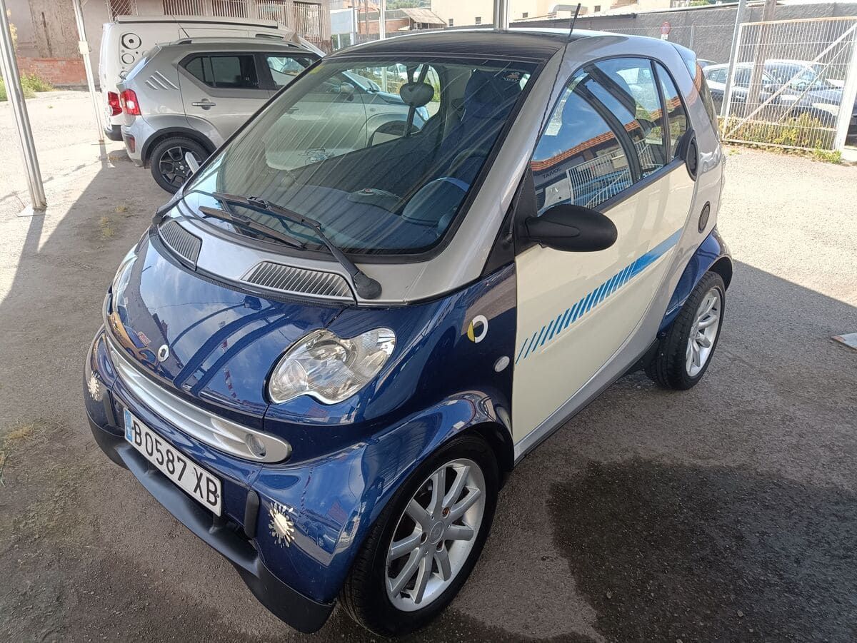 Coche compacto plateado aparcado en un estacionamiento, visto desde el lado delantero izquierdo.