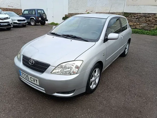 Un Toyota Corolla plateado está estacionado en un estacionamiento.