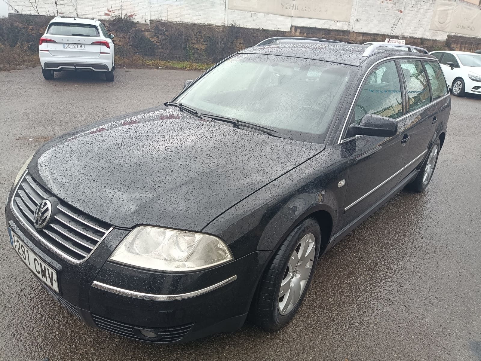 Volkswagen Passat negro en un estacionamiento en un día lluvioso.