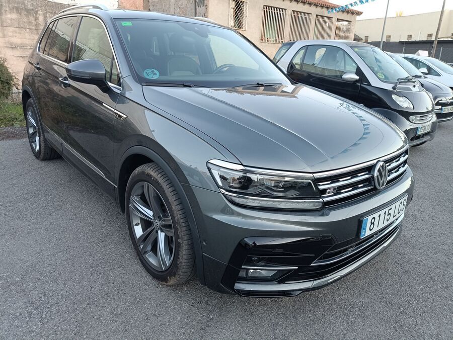 SUV Volkswagen Tiguan gris estacionado afuera, otros autos al fondo.