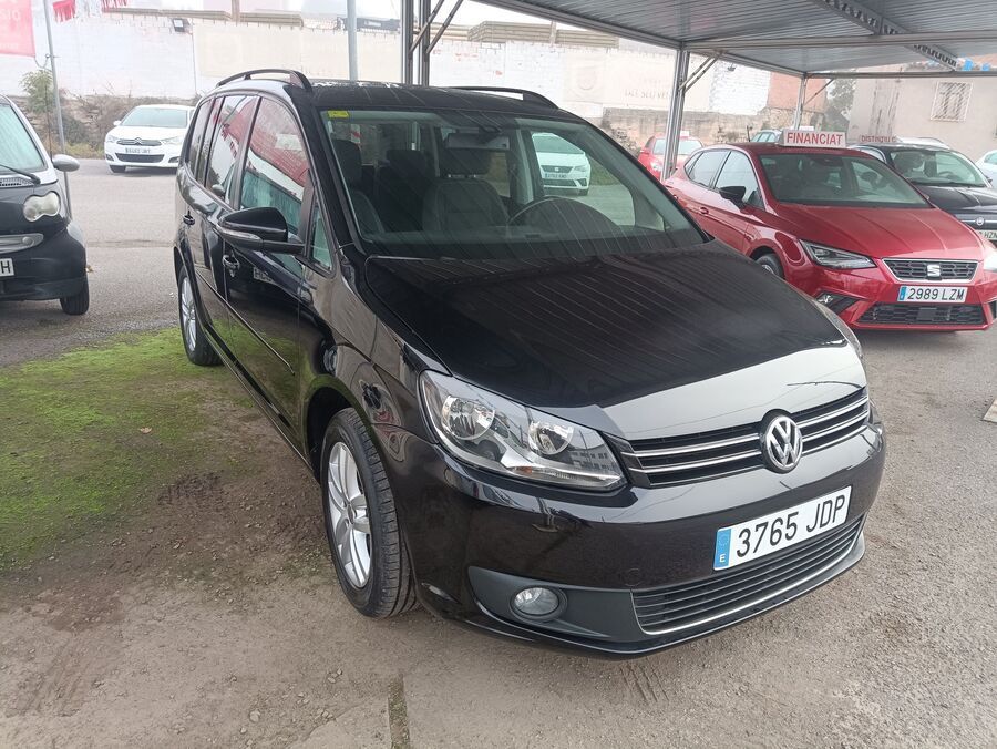 Volkswagen Touran negro aparcado al aire libre junto a otros coches.