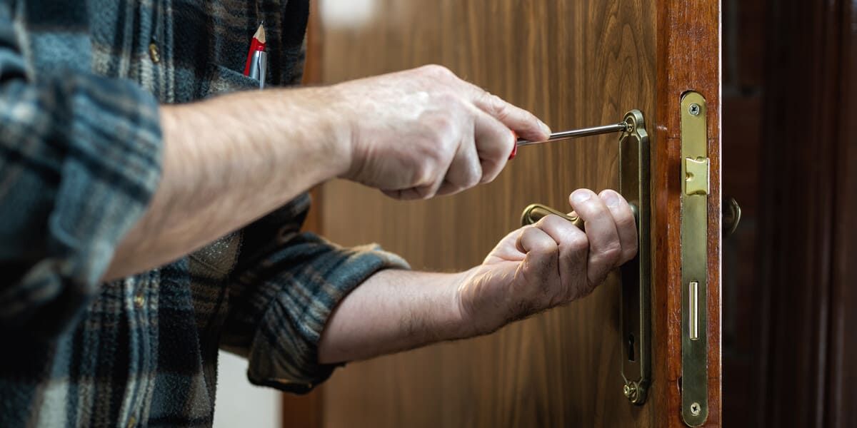 Una persona está usando un destornillador para abrir la cerradura de una puerta.