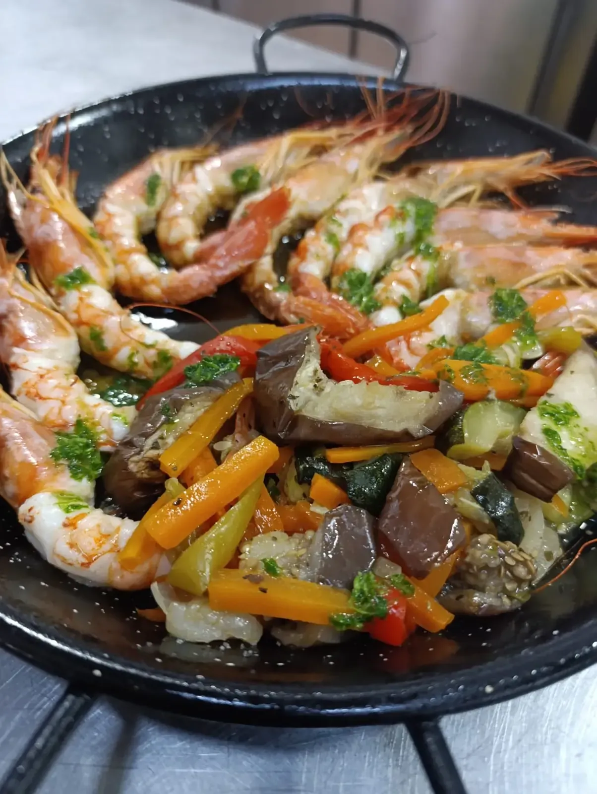 Plato de camarones y verduras en sartén. Camarones con hierbas y verduras salteadas.