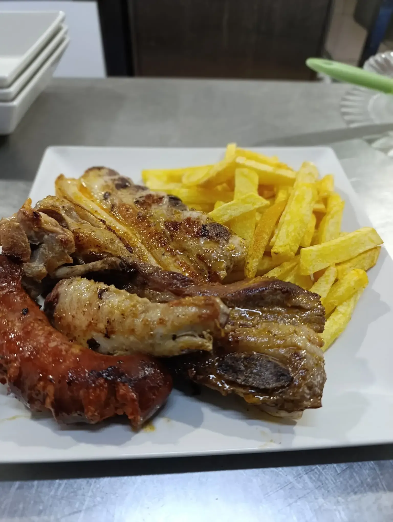Plato de carnes a la parrilla y patatas fritas en un plato blanco.