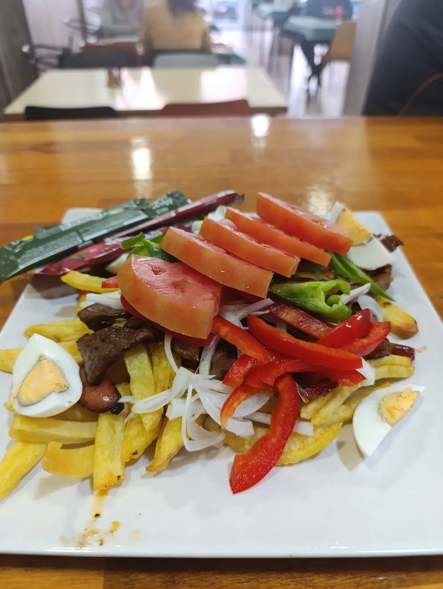 Plato de comida: patatas fritas, carne, verduras y huevos cocidos.