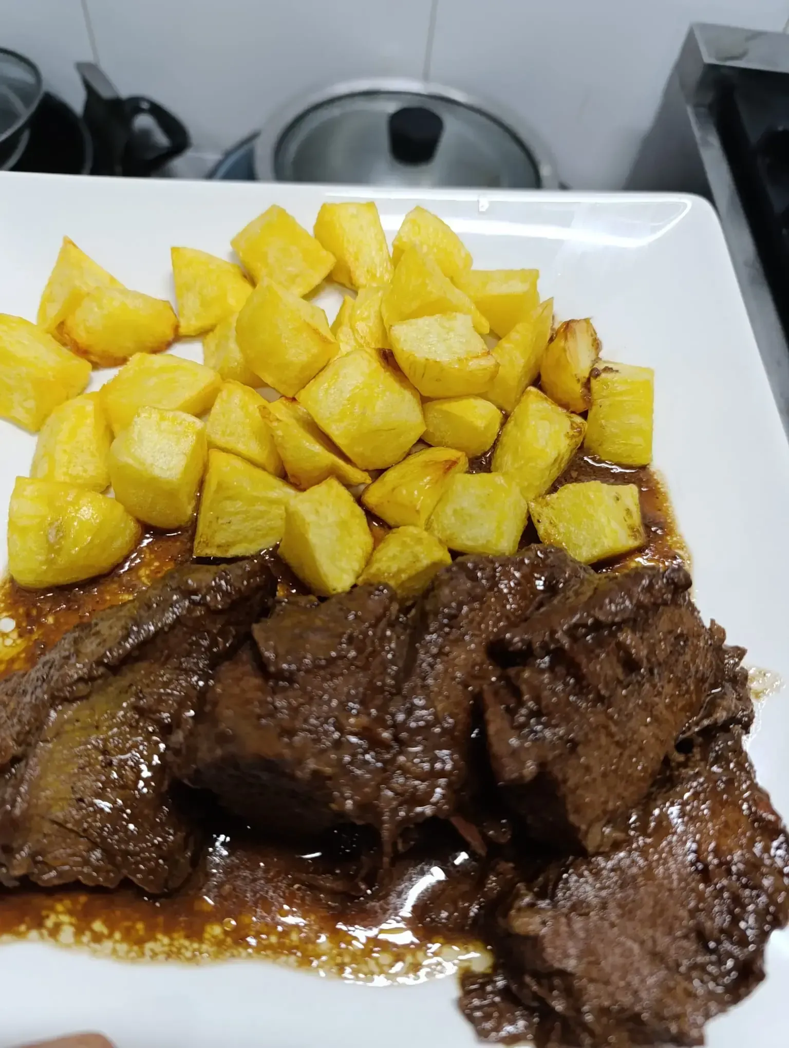 Plato con carne estofada y patatas fritas doradas.