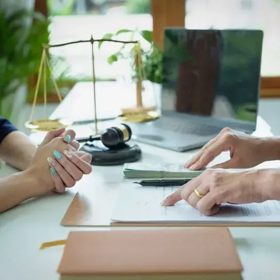 Dos personas están sentadas en una mesa con una computadora portátil y un mazo de juez.