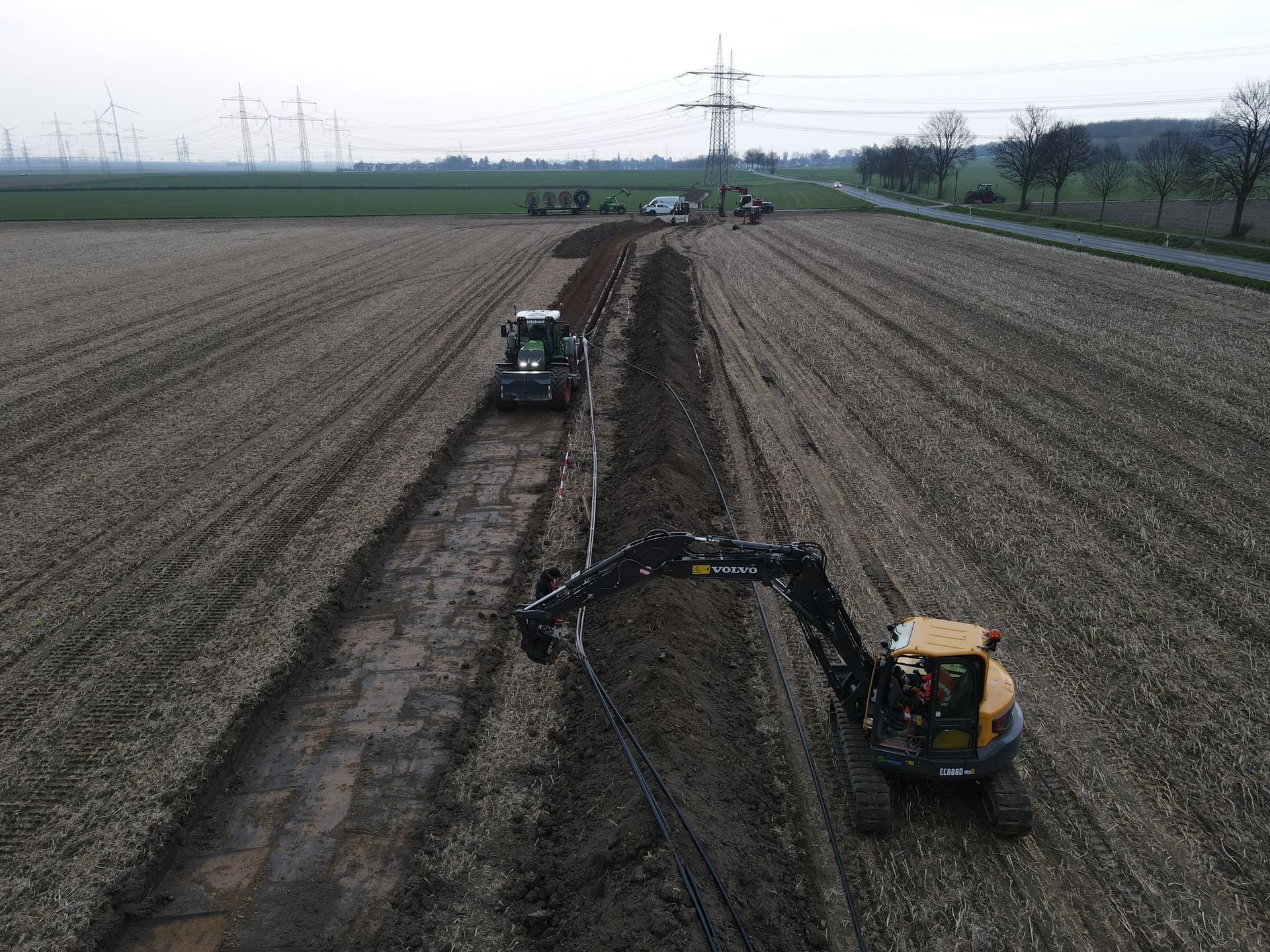 Eine Luftaufnahme eines Traktors und Baggers, die auf einem schlammigen Feld arbeiten
