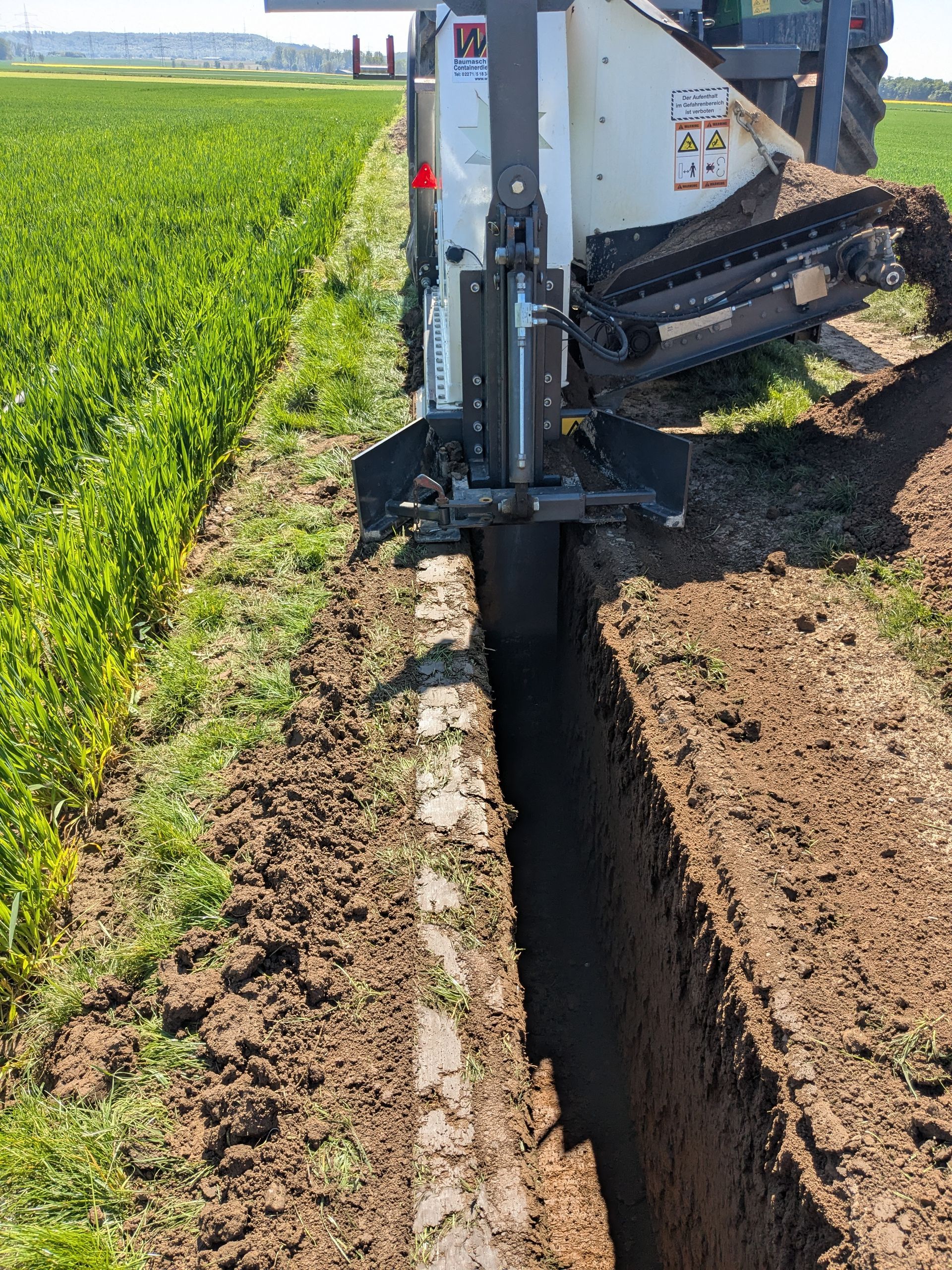 Ein Traktor gräbt einen Graben auf einem Feld