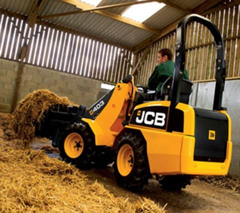 Ein Mann fährt einen JCB-Traktor in einer Scheune