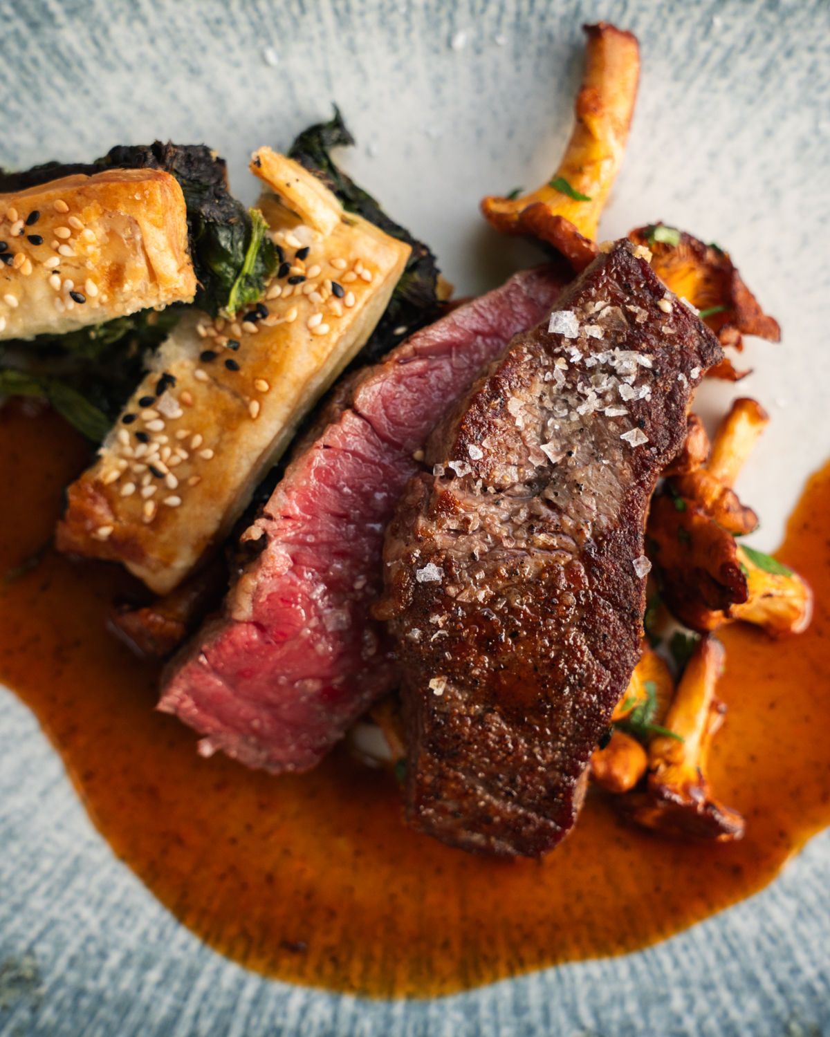 Gebratene Steakstreifen mit Sesam-Gemüse in brauner Sauce auf einem weißen Teller