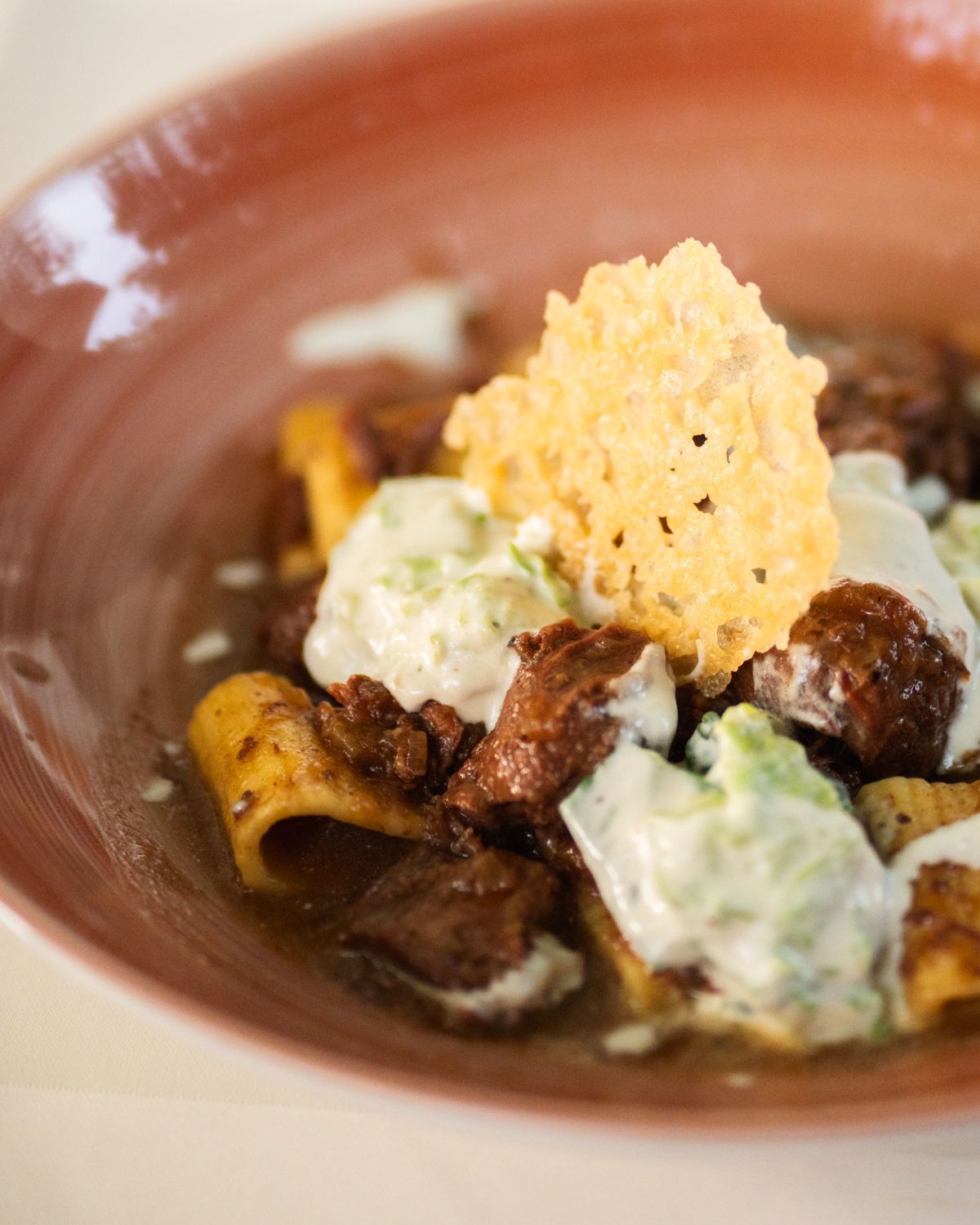 Braune Schüssel mit gegrillten Champignons, grüner Sauce und einer knusprigen Käsetuile als Topping