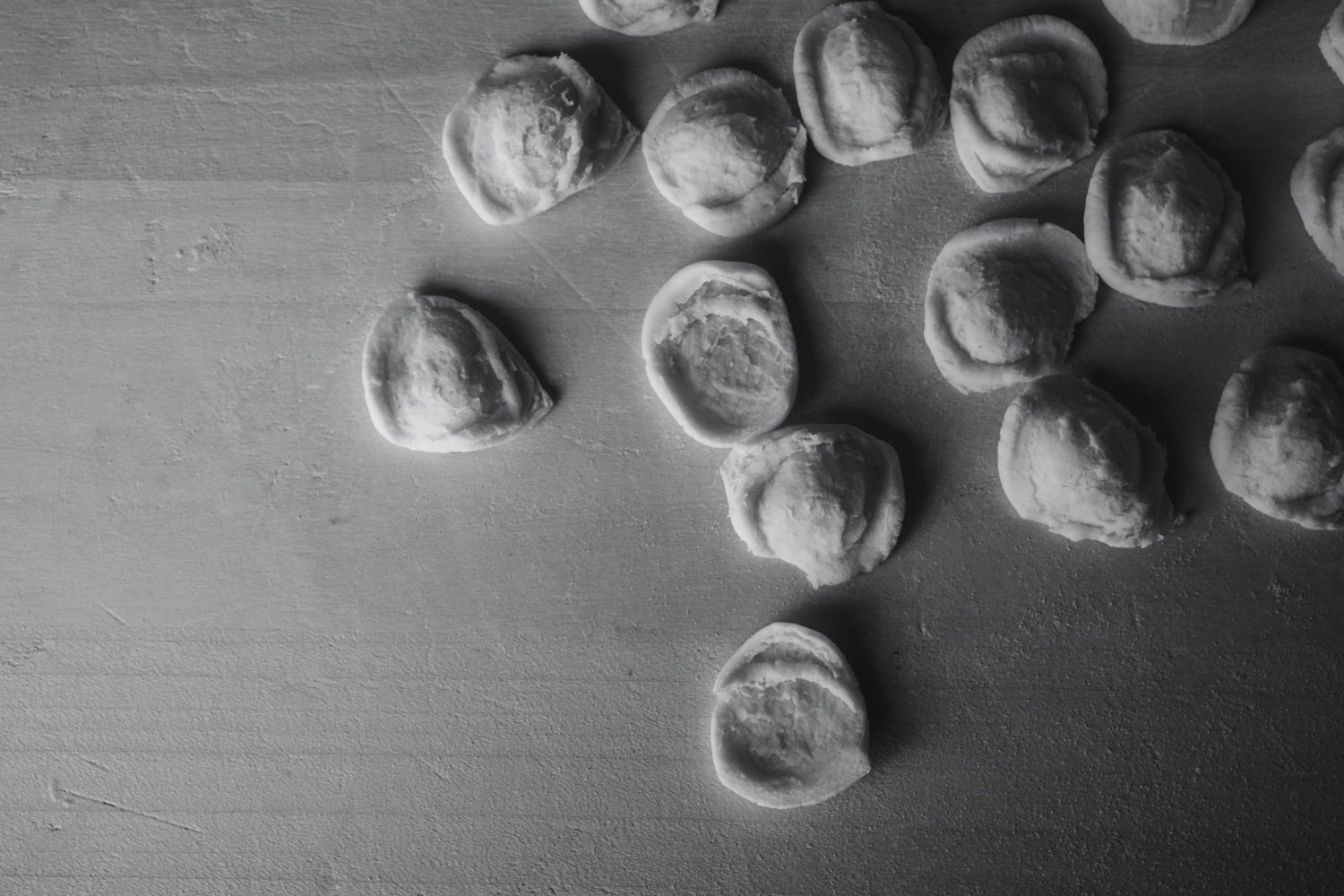 Schwarz-Weiß-Nahaufnahme von kleinen, runden Kieselsteinen, die auf einer glatten Oberfläche verstreut sind
