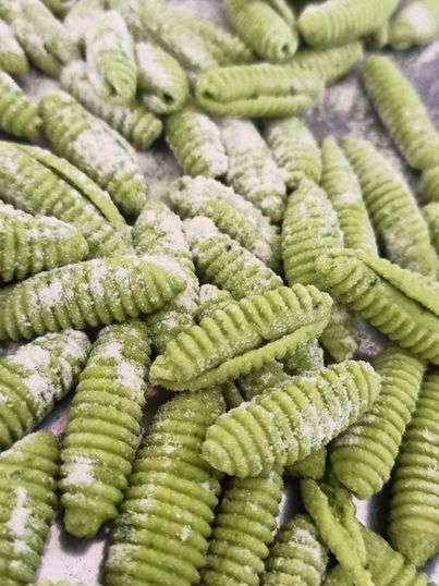 Grüne, geriffelte Nudeln, mit Mehl bestreut.