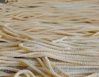 Nahaufnahme von Strängen getrockneter, strukturierter Pasta.