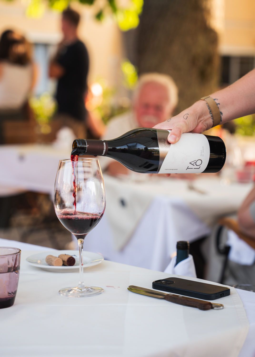 Wein wird während einer Mahlzeit am Restauranttisch in ein Glas eingeschenkt.