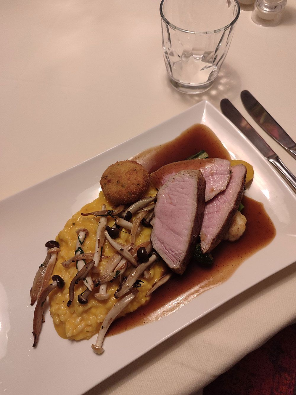 Teller mit geschnittenem Fleisch, Pilzen und gelbem Püree mit Soße.