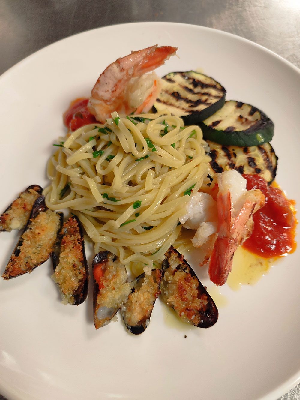 Teller Pasta mit gegrilltem Gemüse, Garnelen, Muscheln und Tomatensoße.