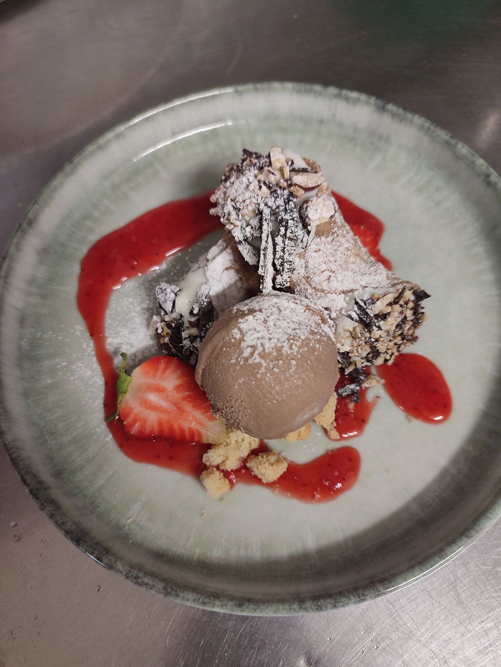 Cannoli-Dessert mit Eis, Erdbeersauce und frischen Erdbeeren auf einem Teller.