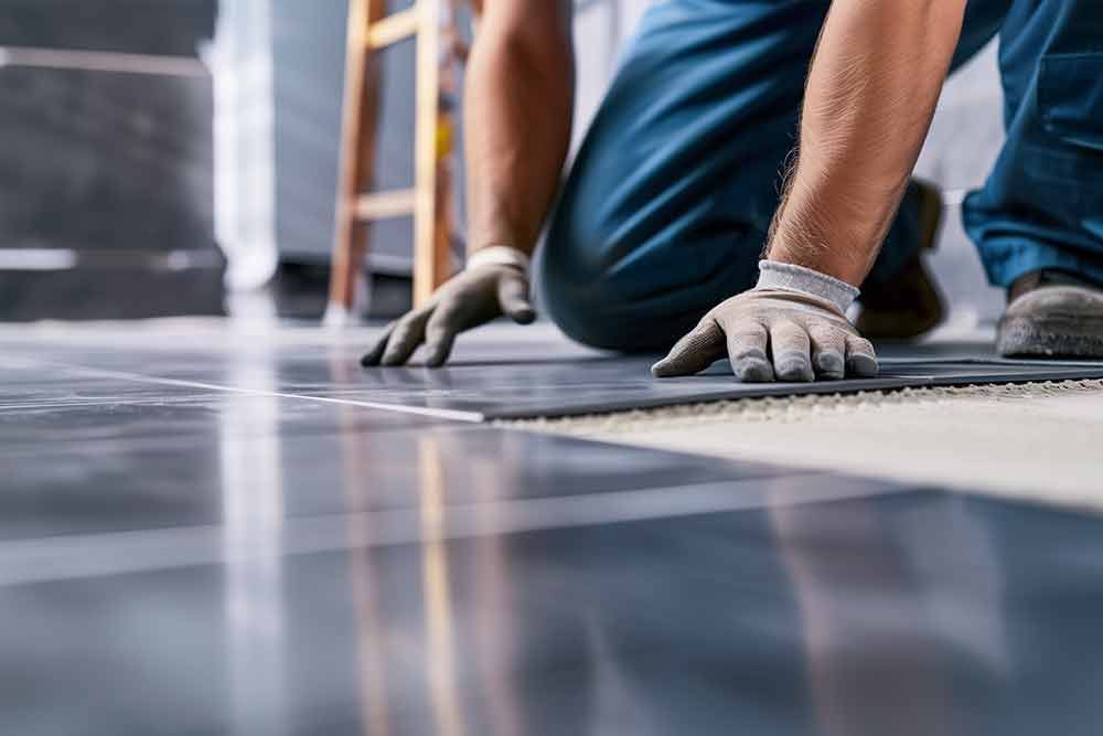 Ein Mann kniet nieder, um einen Fliesenboden zu verlegen.