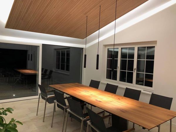 Ein Esszimmer mit einem langen Holztisch und Stühlen