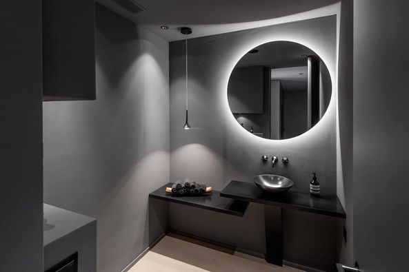 Ein Badezimmer mit rundem Spiegel und Waschbecken.