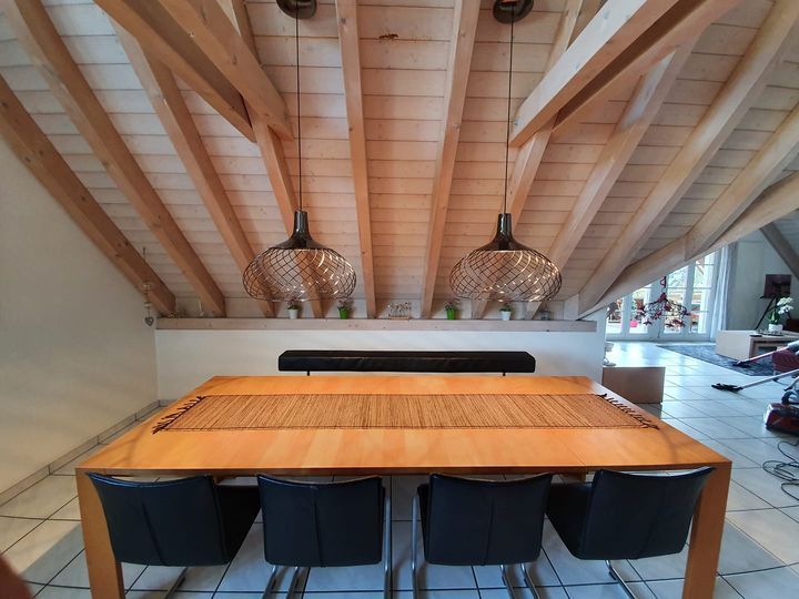 Ein Esszimmer mit Tisch und Stühlen unter einer Holzdecke