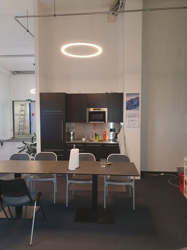 Eine Küche mit Tisch und Stühlen und einer von der Decke hängenden Lampe.