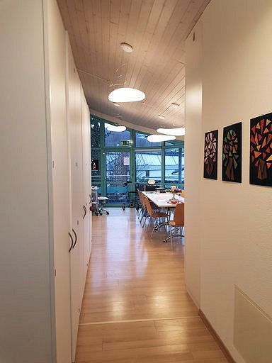 Ein langer Flur, der zu einem Esszimmer mit Tischen und Stühlen führt.