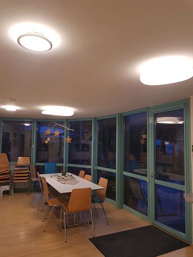 Ein Esszimmer mit Tisch und Stühlen und vielen Fenstern.