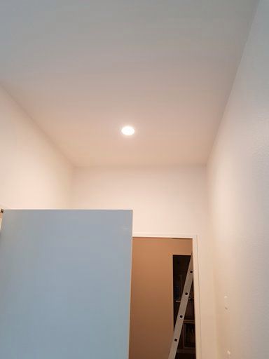 Ein Flur mit einer Leiter und einer Lampe an der Decke.