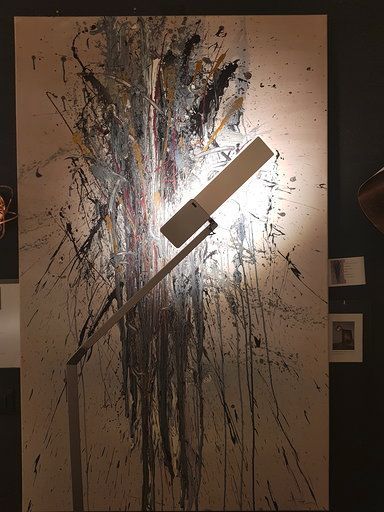 Eine Lampe steht vor einem großen Gemälde an einer Wand.