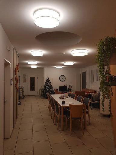 Ein großer Raum mit einem Tisch und Stühlen und einer Uhr an der Decke.