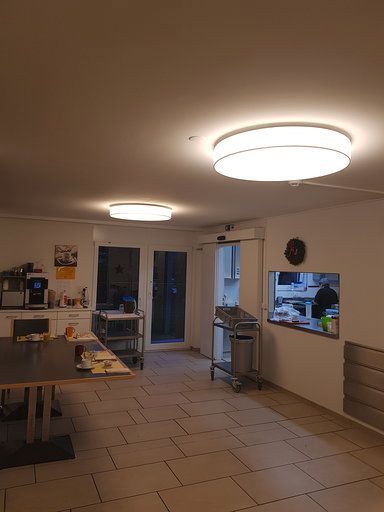 Ein großer Raum mit Tischen und Stühlen und einer Deckenleuchte.