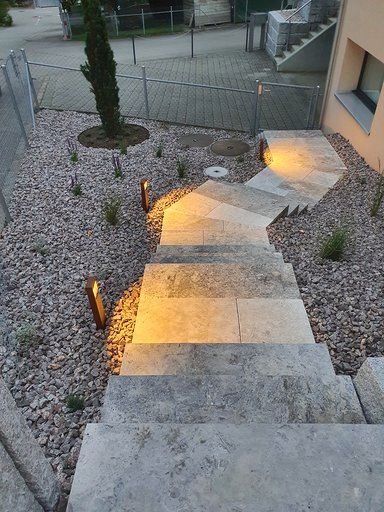 Eine Treppe, die zu einem von Felsen und Pflanzen umgebenen Gebäude führt.