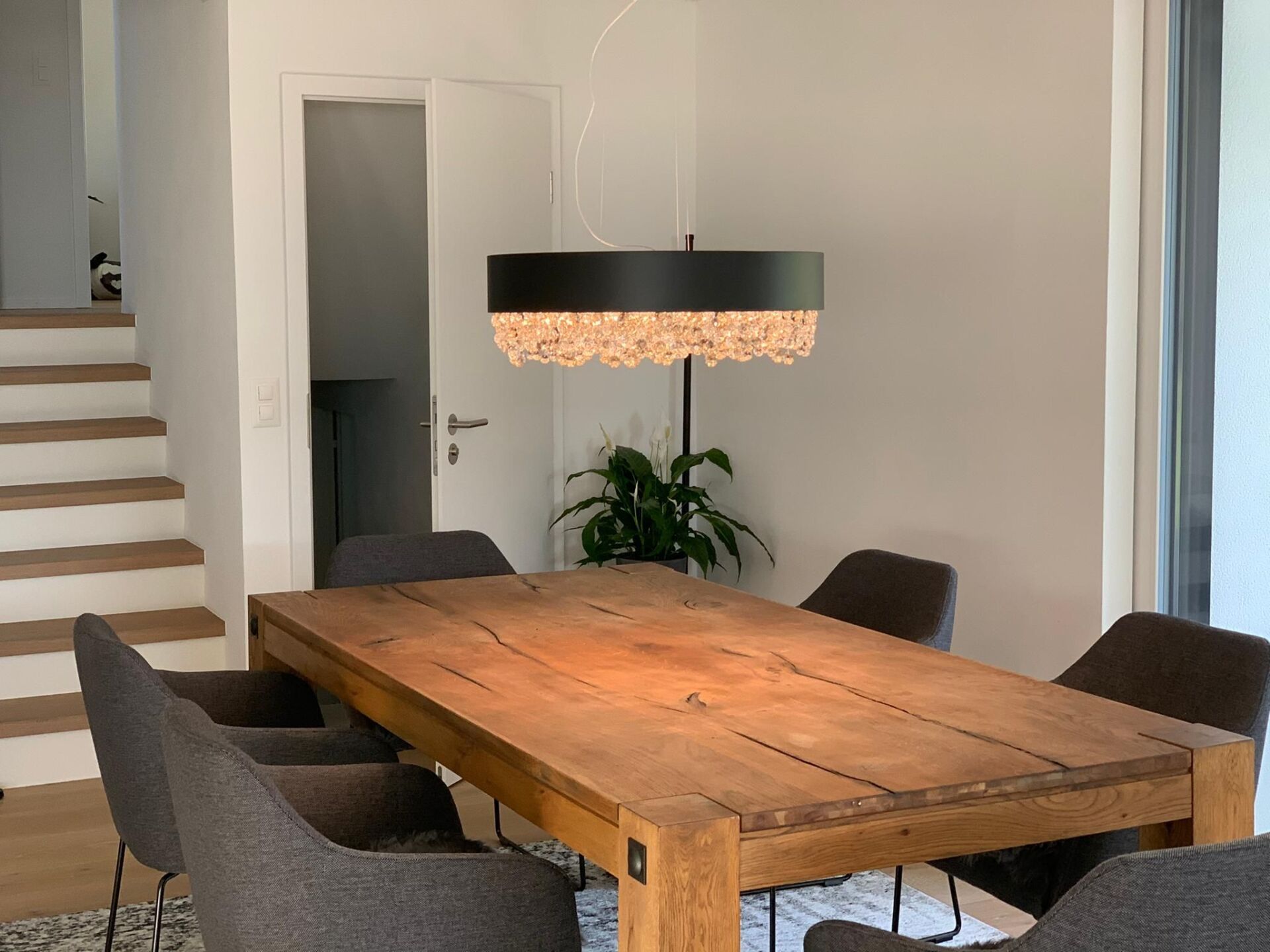 Ein Esszimmer mit einem Holztisch und Stühlen und einer Treppe.