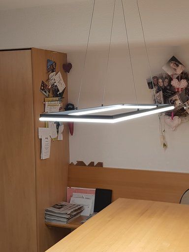 Über einem Holztisch hängt eine Lampe von der Decke.