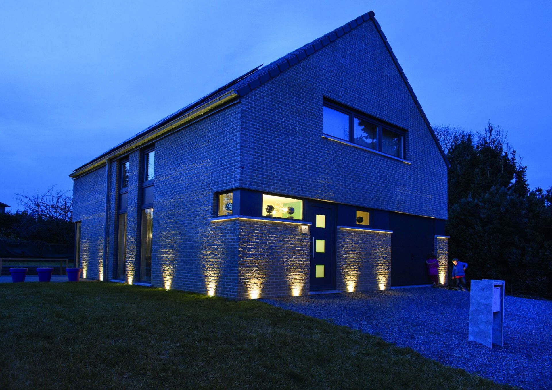 Ein Haus ist nachts beleuchtet, im Hintergrund ein blauer Himmel