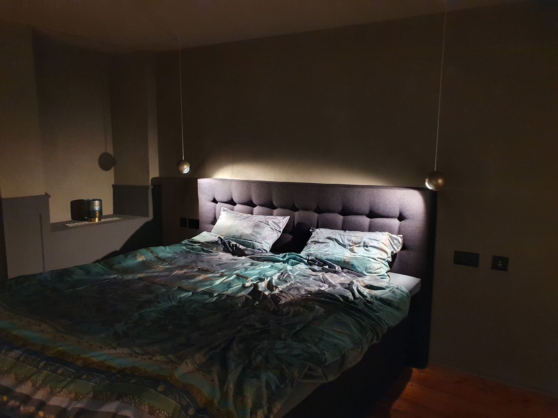 Ein Bett mit Kopfteil und Kissen in einem dunklen Raum.