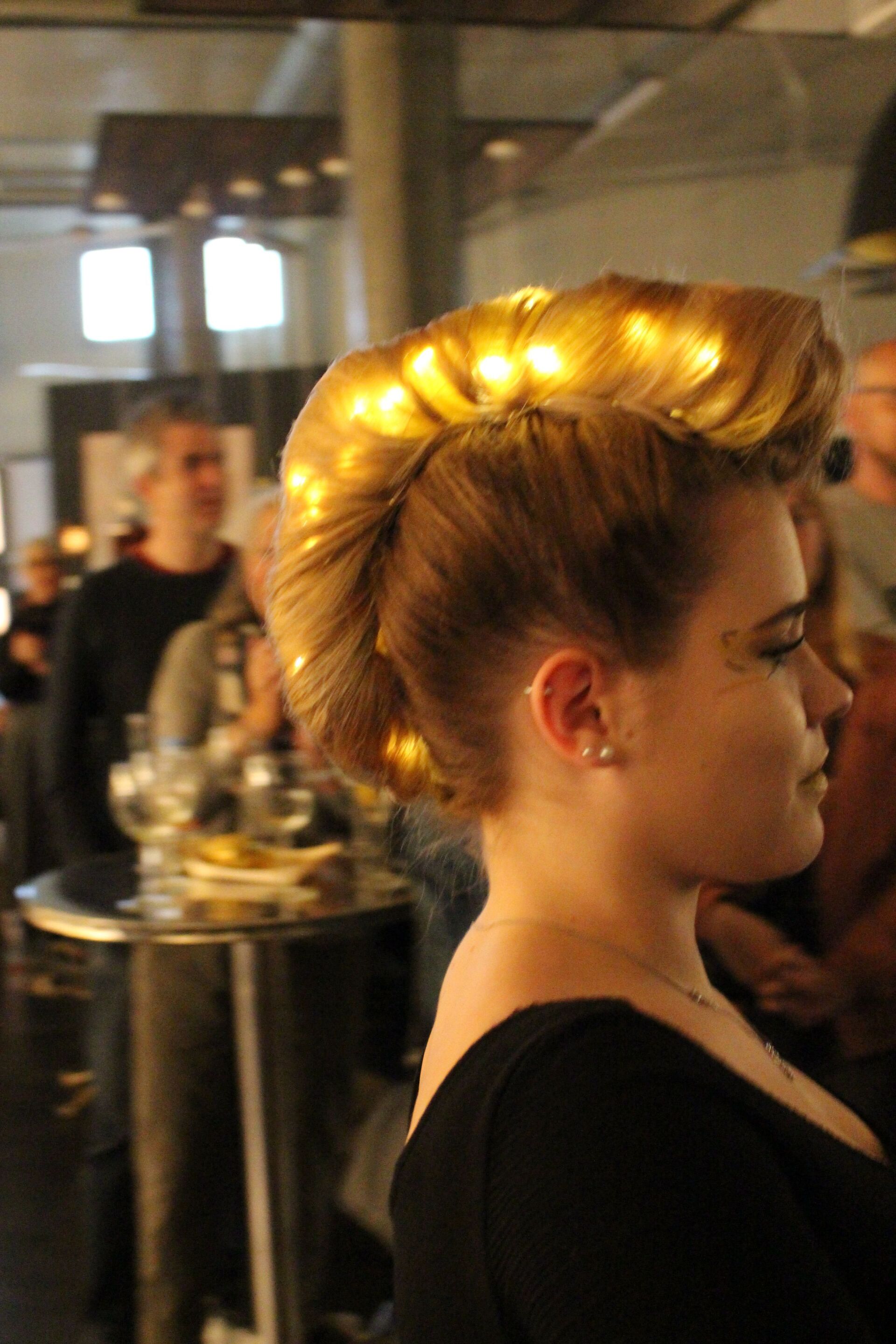 Eine Frau in einem schwarzen Kleid trägt einen Dutt mit Lichtern darin