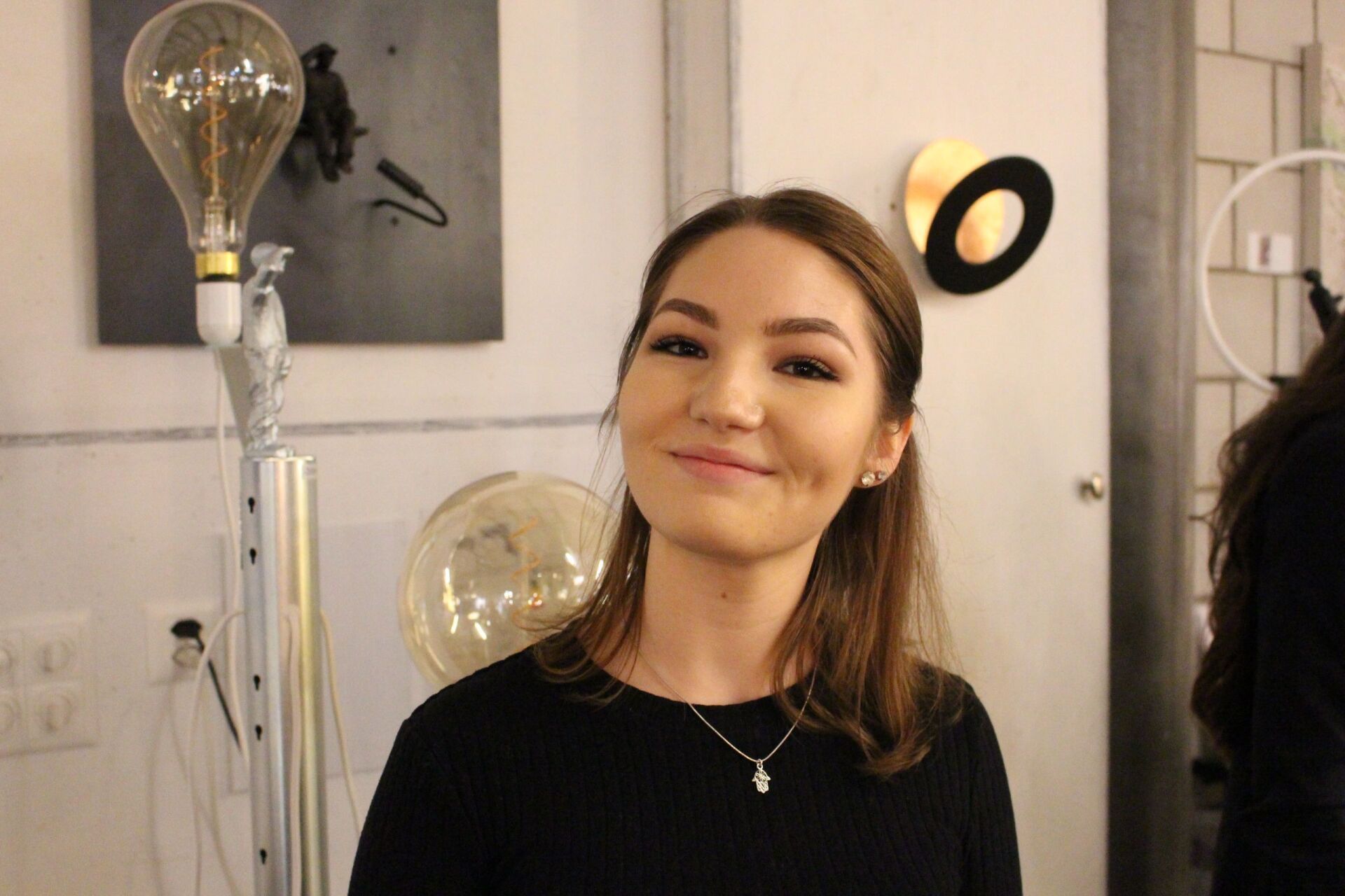 Eine Frau steht vor einer Glühbirne und lächelt.