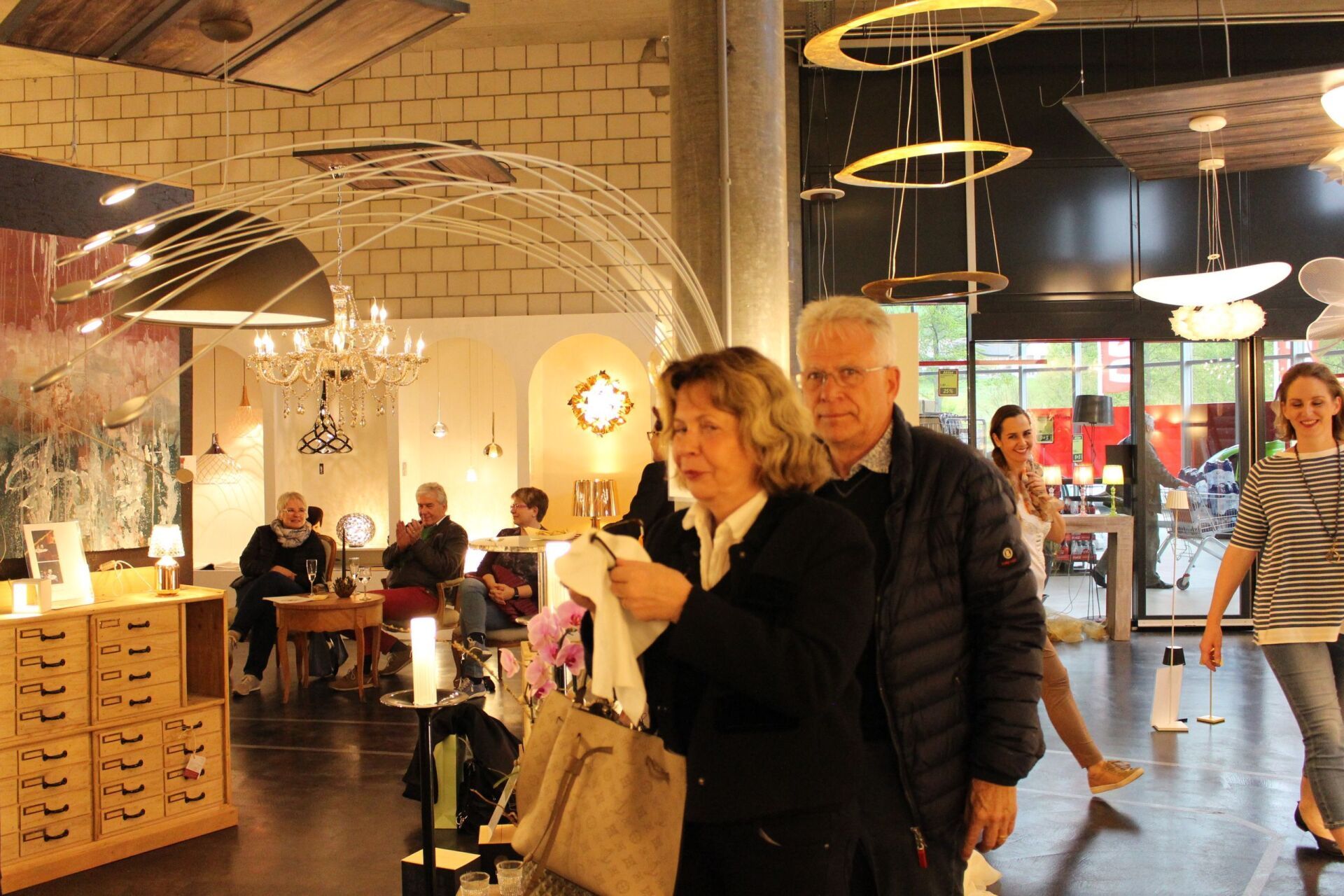 Ein Mann und eine Frau stehen in einem Raum, von dessen Decke viele Lichter hängen.