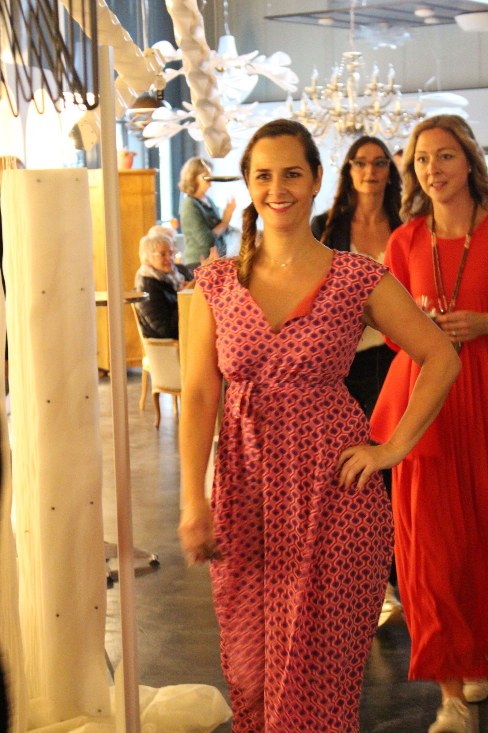 Eine Frau in einem rosa Kleid steht neben einer anderen Frau in einem roten Kleid.