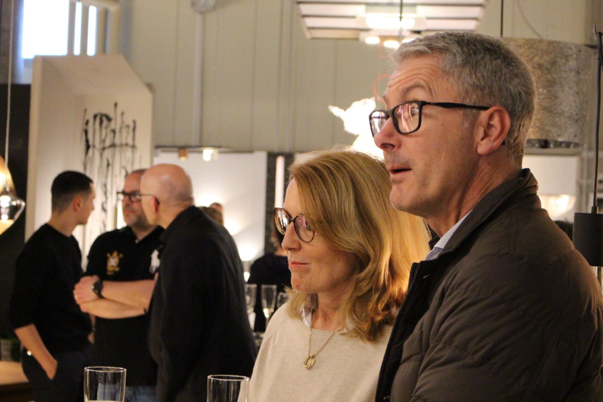 Ein Mann und eine Frau mit Brille stehen nebeneinander in einem Raum.