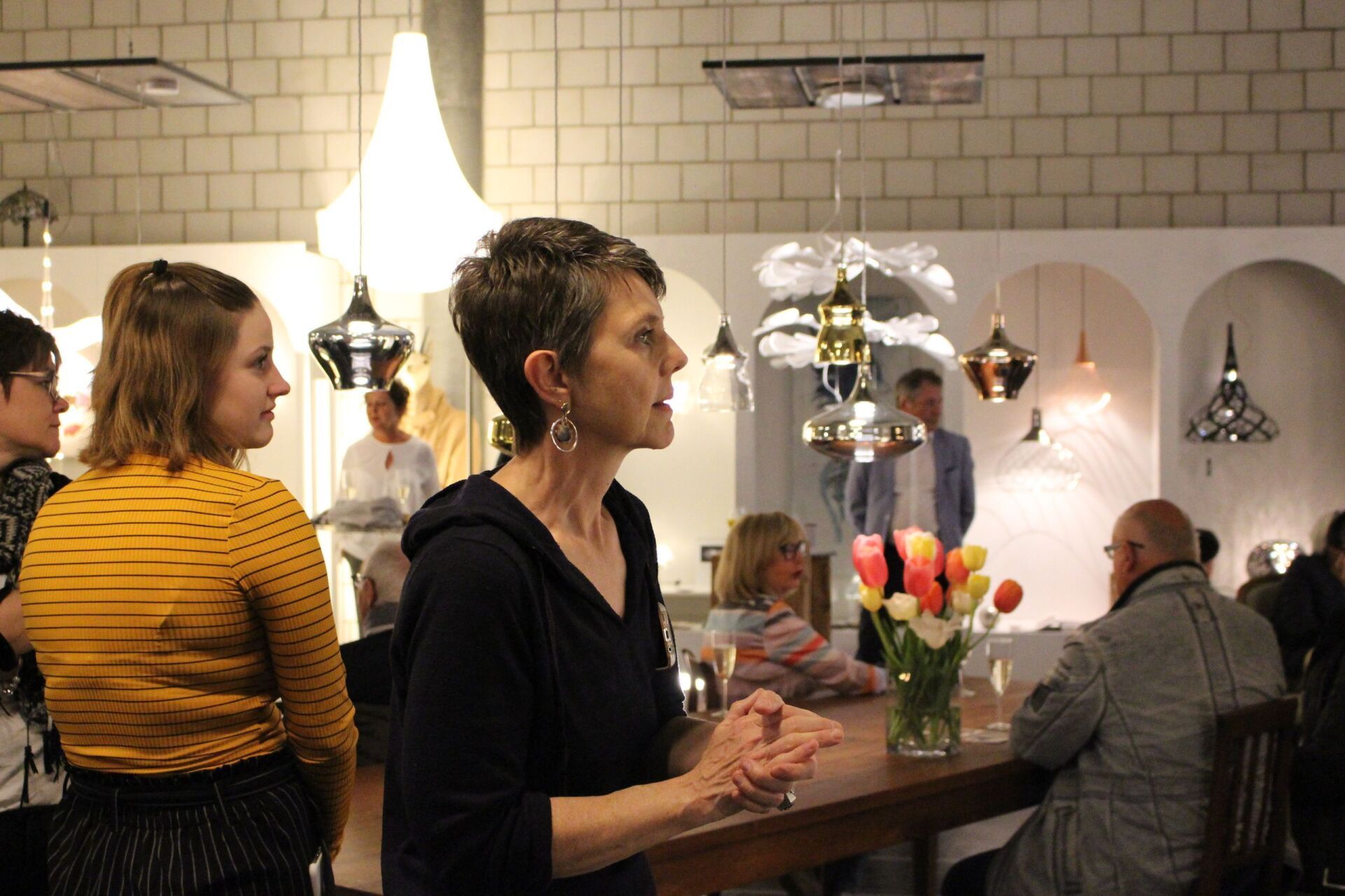 Eine Frau steht in einer Bar und unterhält sich mit einer Gruppe von Leuten.