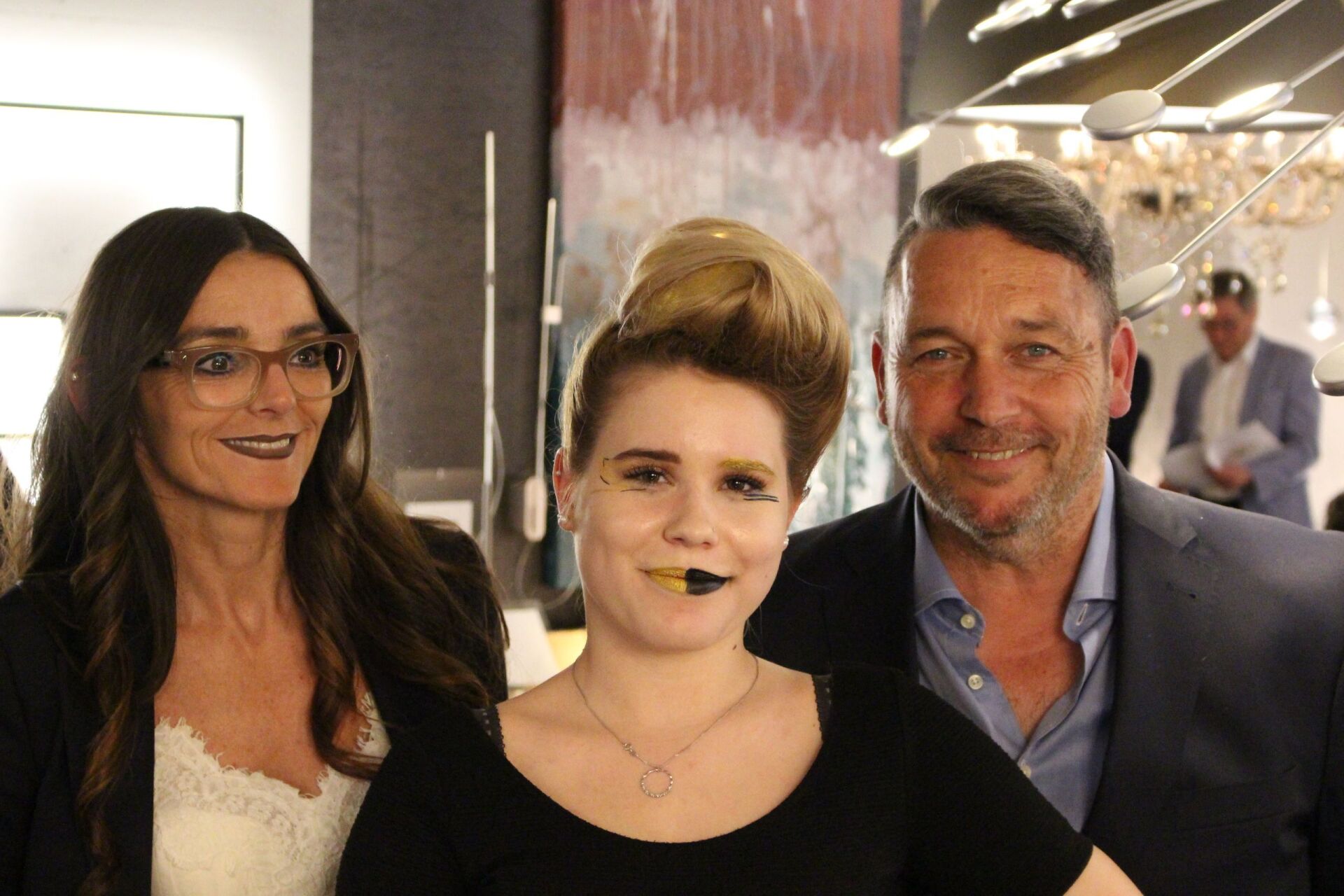 Ein Mann und zwei Frauen posieren in einem Raum für ein Foto.